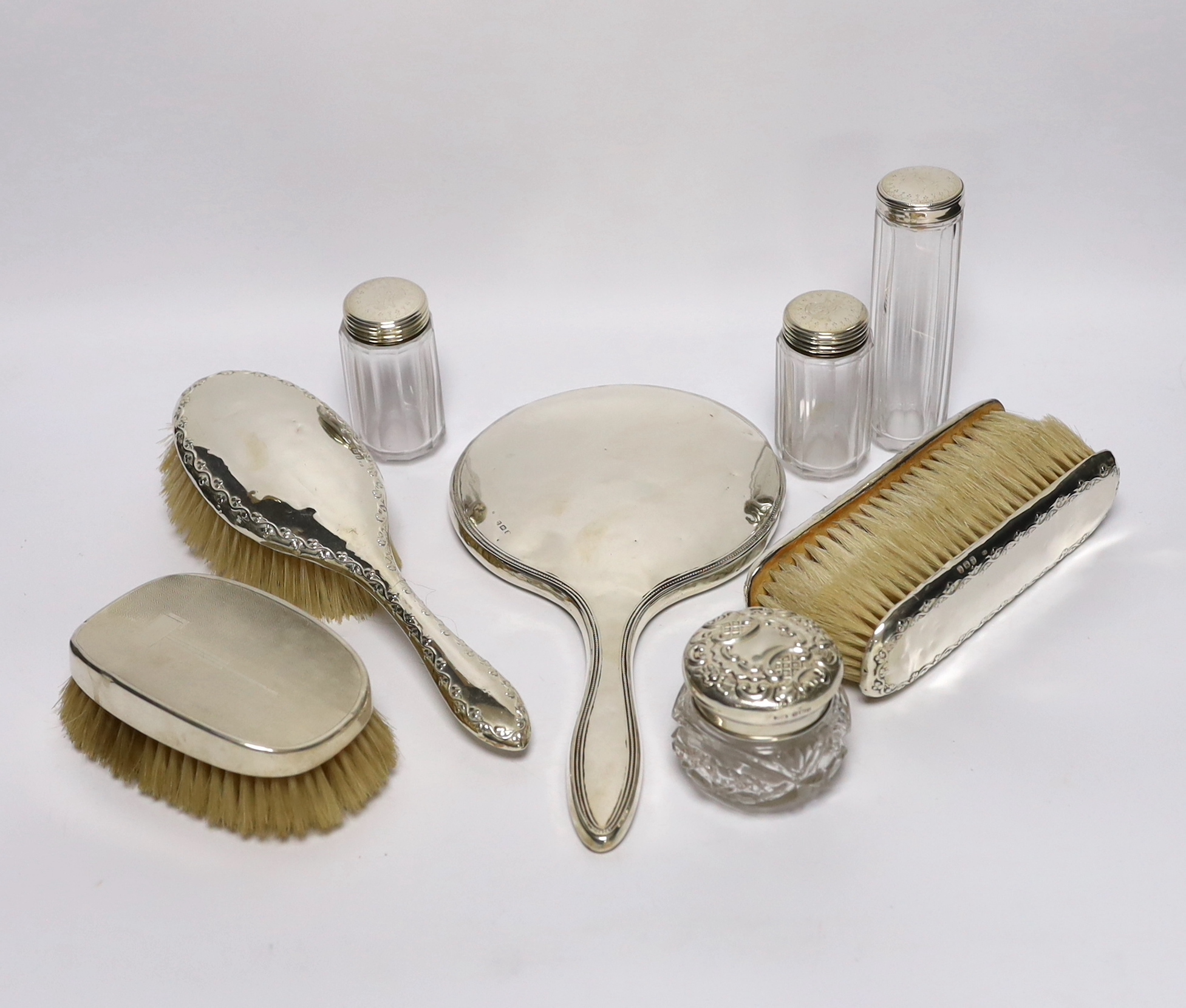 A silver mounted hand mirror and four similar brushes, together with four mounted glass toilet jars.